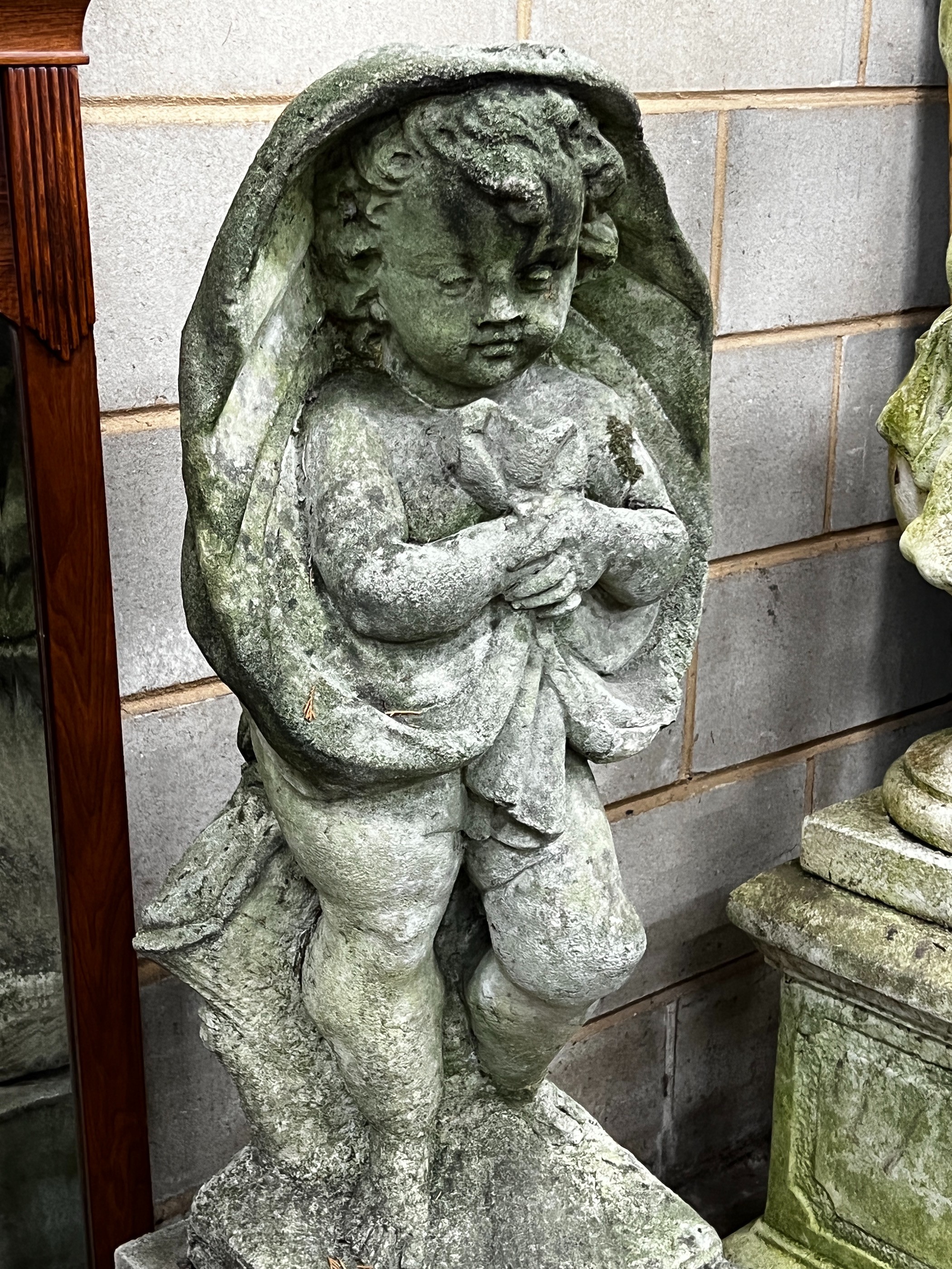 A large weathered reconstituted stone garden figure, cherub in drapery, height 122cm